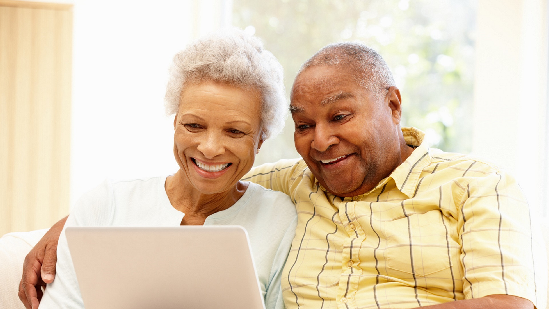 Two seniors smiling at a laptop